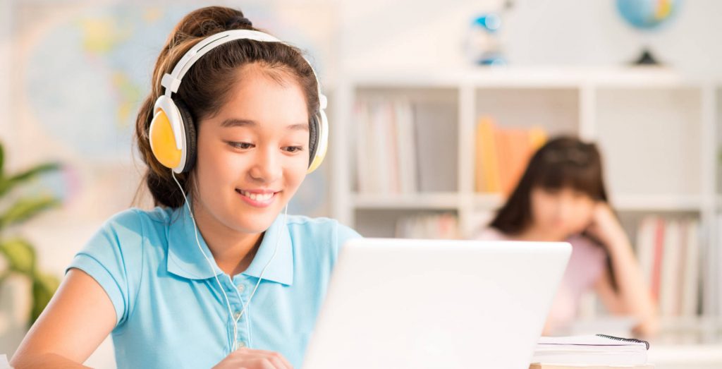 image of student wearing headphones, working on laptop